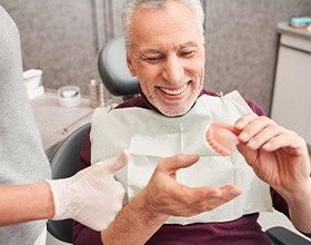 Man in dental chair smiling and receiving dentures