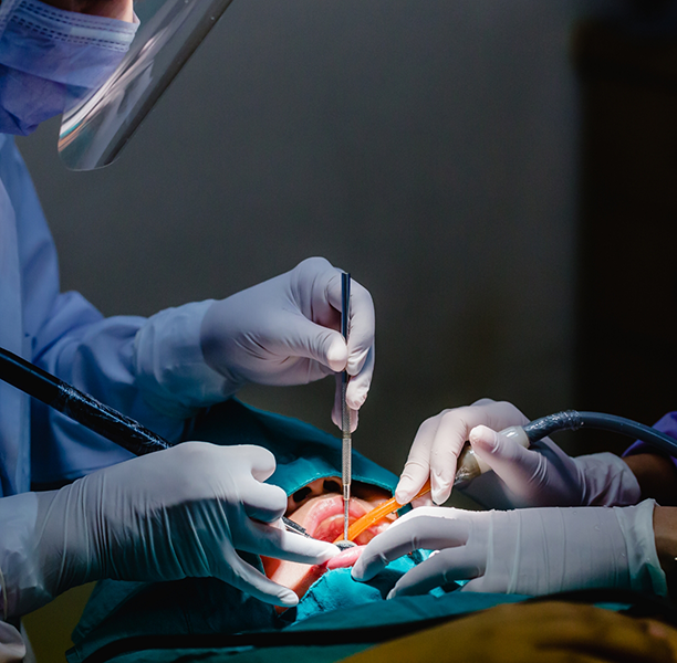 Dentist and assistant performing a dental implant procedure on a patient