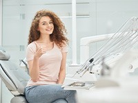 Female dental patient in pink shirt giving thumbs up