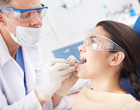 A dentist closely checking a woman’s gums