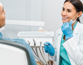 Smiling dentist looking at patient in treatment chair