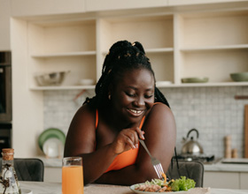 Woman smiling while eating lunch in kitchen