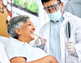 Dentist showing smiling patient reflection in mirror