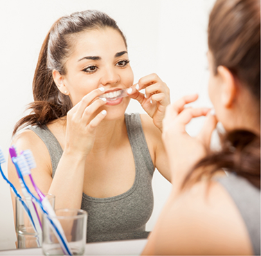 Woman placing a whitening tray over her teeth