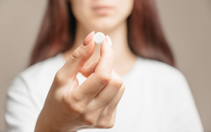 Woman holding a round pill for oral conscious sedation